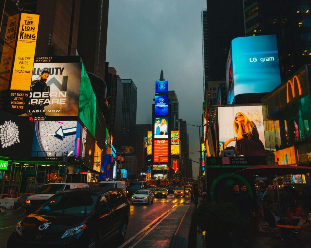 the LED screens on the tower of a busy road displaying different adds.